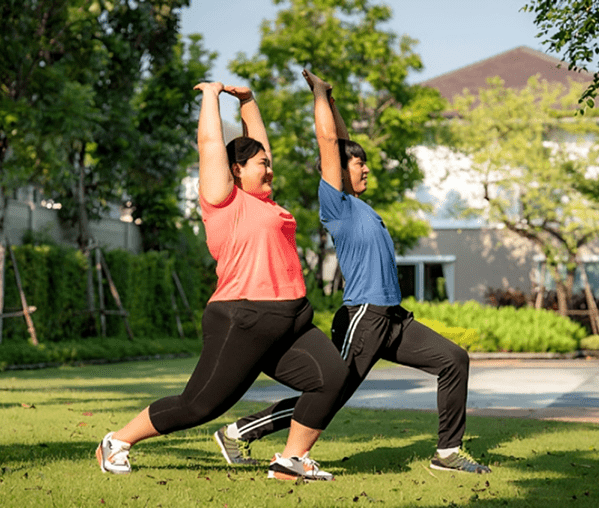 Two people practicing yoga outdoors